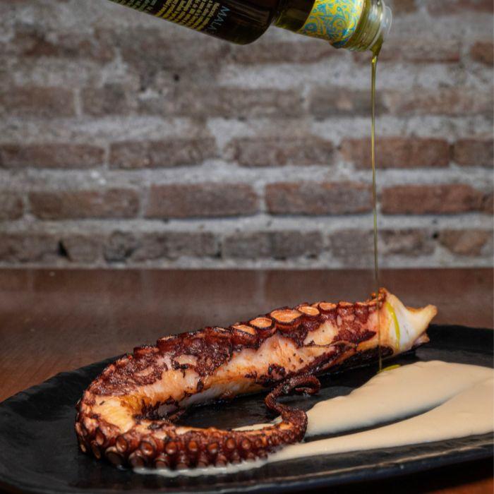 Pulpo a la brasa regado con aceite de oliva virgen extra sobre parmentier en La Auténtica Carmela, Granada