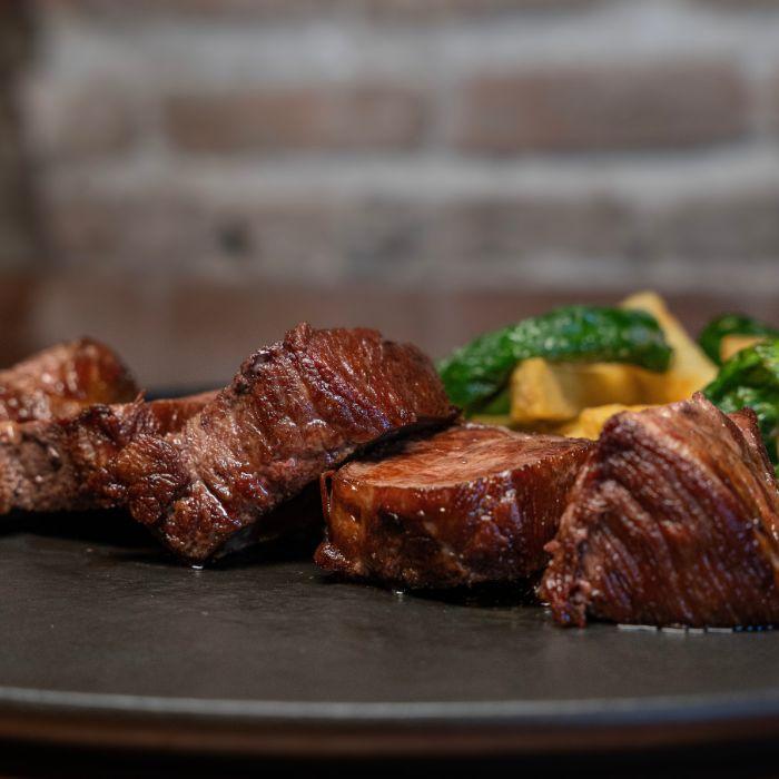 Presa ibérica a la brasa con patatas fritas y pimientos de Padrón en La Auténtica Carmela