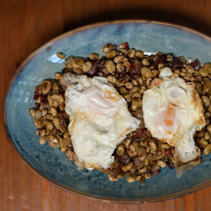 Habitas baby salteadas con jamón y huevos fritos en La Auténtica Carmela