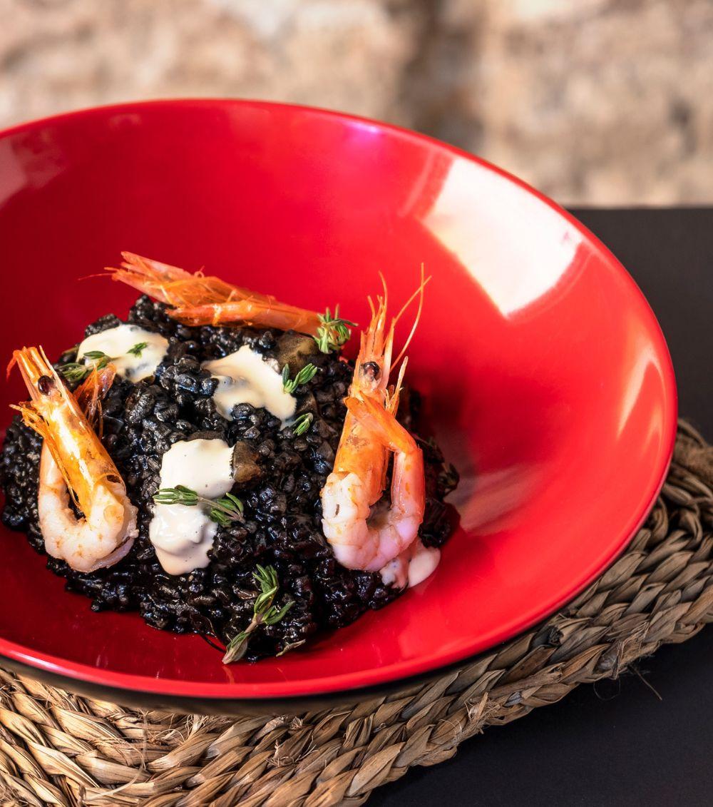 Arroz negro con gambas, choco y alioli servido en cuenco rojo en La Auténtica Carmela, Granada