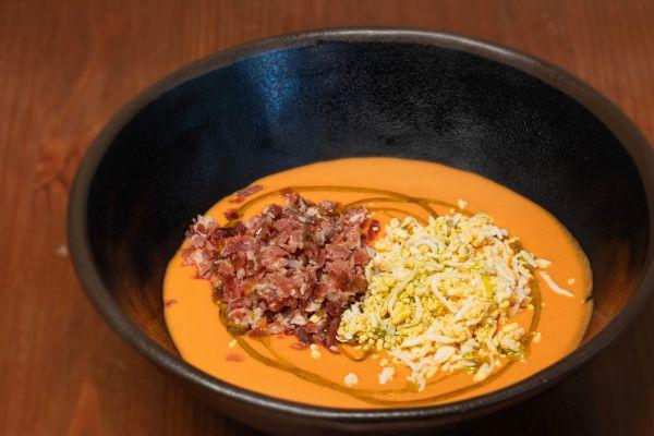 Salmorejo con jamón ibérico y huevo rallado servido en cuenco de barro en La Auténtica Carmela