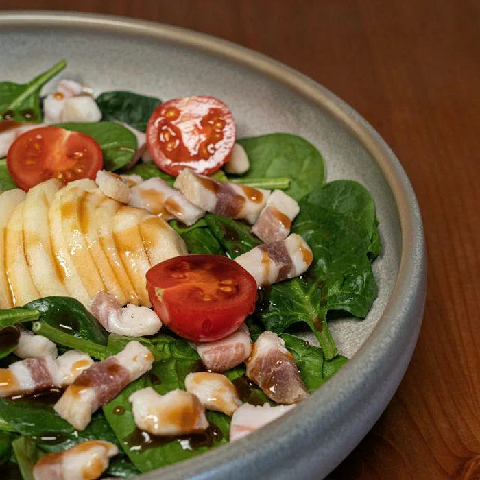 Ensalada de espinacas con manzana, tomate cherry y jamón ibérico en La Auténtica Carmela