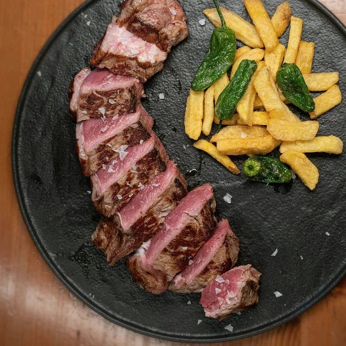 Entrecot a la brasa con patatas fritas y pimientos de Padrón en La Auténtica Carmela