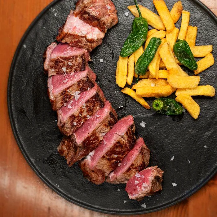Entrecot a la brasa con patatas fritas y pimientos de Padrón en La Auténtica Carmela