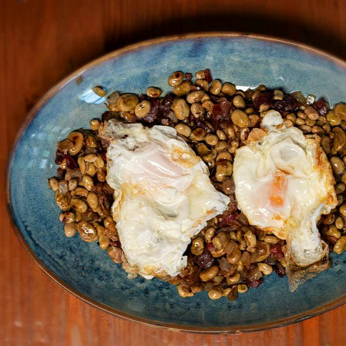 Habitas baby salteadas con jamón y huevos fritos en La Auténtica Carmela