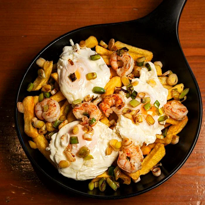 Huevos rotos con gambones y ajetes en La Auténtica Carmela