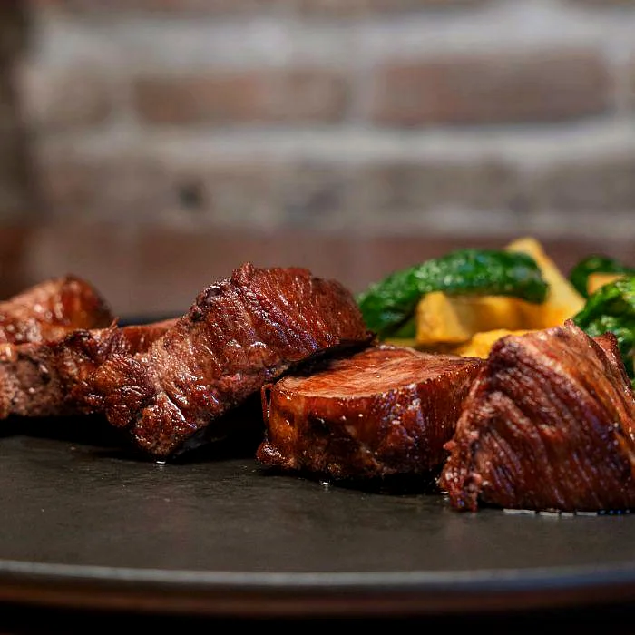 Presa ibérica a la brasa con patatas y pimientos en La Auténtica Carmela
